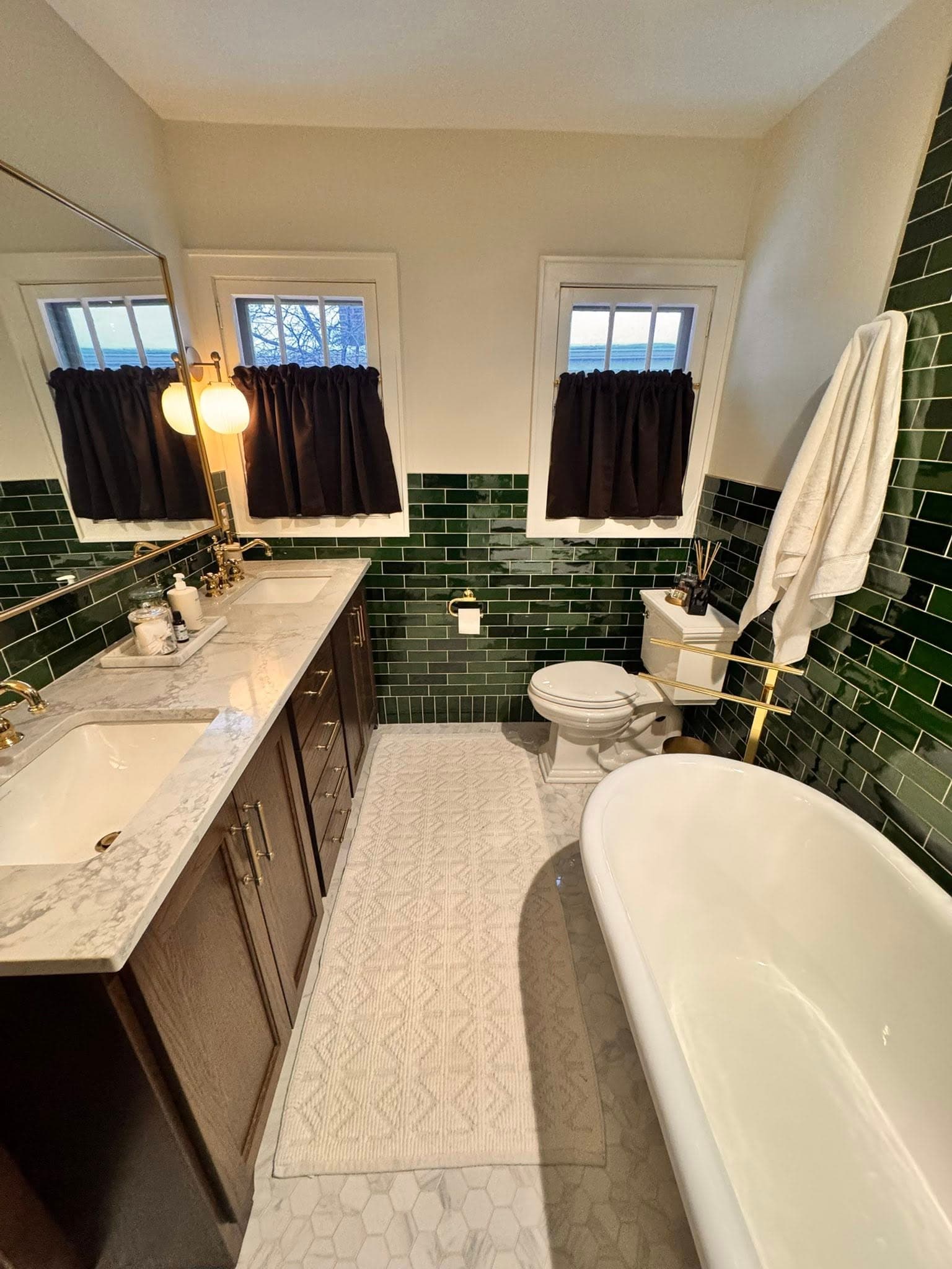 Full bathroom remodel with dark green subway tile, clawfoot tub, and marble floor